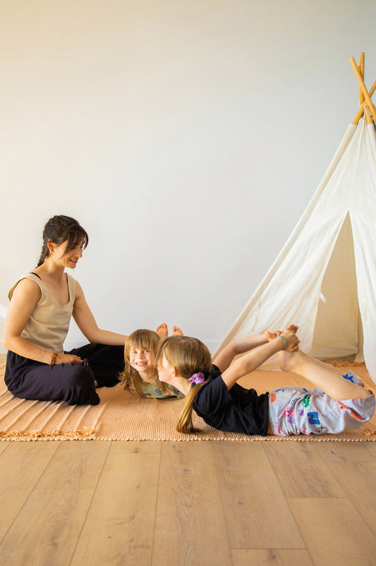 photo d'une femme et deux petites filles qui partagent un moment convivial et pratiquent sur un tapis XL éco-responsable Mahola.